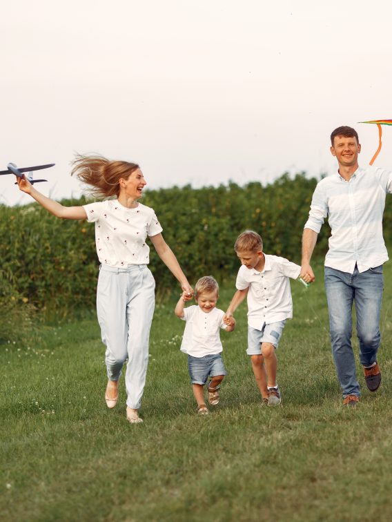 Rodzina chodzi po polu i bawi się zabawkowym samolotem